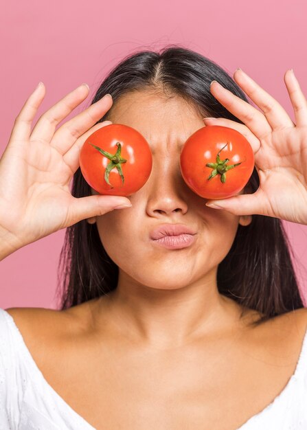 Foto gratuita mujer frunciendo el ceño y sosteniendo tomates