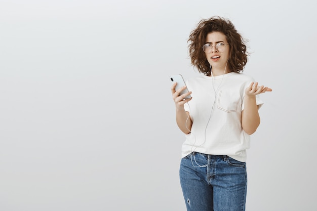 Foto gratuita mujer frustrada y confundida reacciona a un mensaje extraño en el teléfono móvil, no puede entender