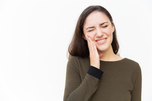 Foto gratuita mujer frustrada con una mueca de dolor tocando la mejilla