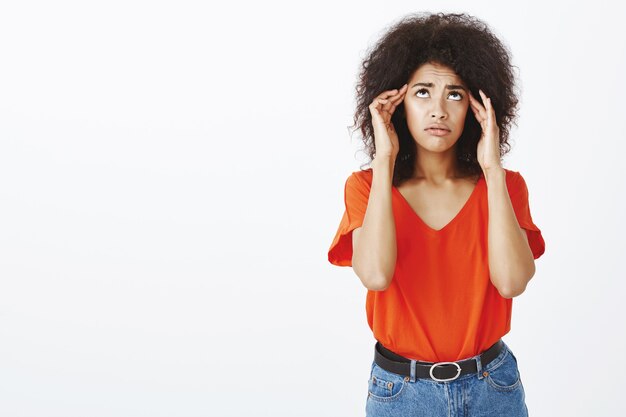 Mujer frustrada con peinado afro posando en el estudio