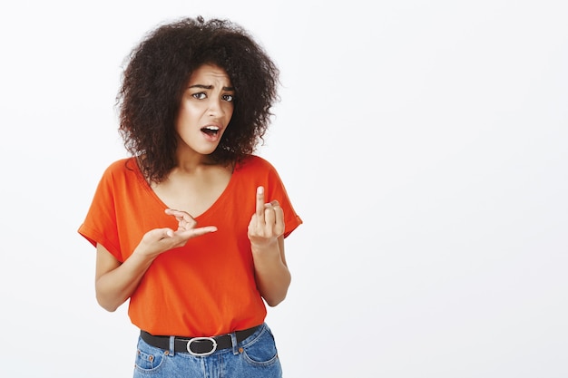 Mujer frustrada con peinado afro posando en el estudio