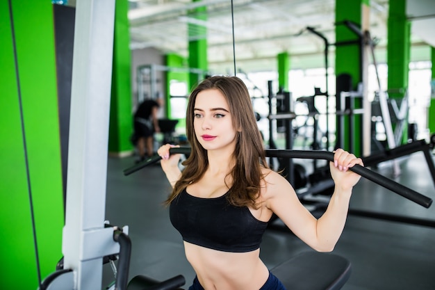 Mujer fuerte está trabajando con simulador deportivo en el moderno centro deportivo de moda