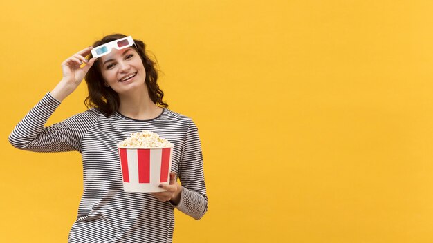 Mujer con gafas 3d sosteniendo un cubo con palomitas de maíz con espacio de copia