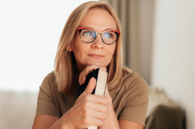 Mujer con gafas en casa sosteniendo el libro durante la cuarentena