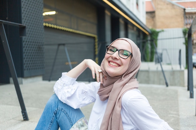 Mujer con gafas y hijab sonriendo
