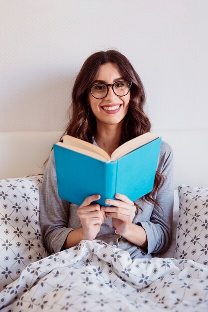 Mujer en gafas leyendo en la cama