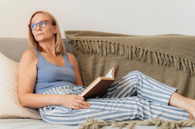 Mujer con gafas leyendo un libro en casa durante la cuarentena