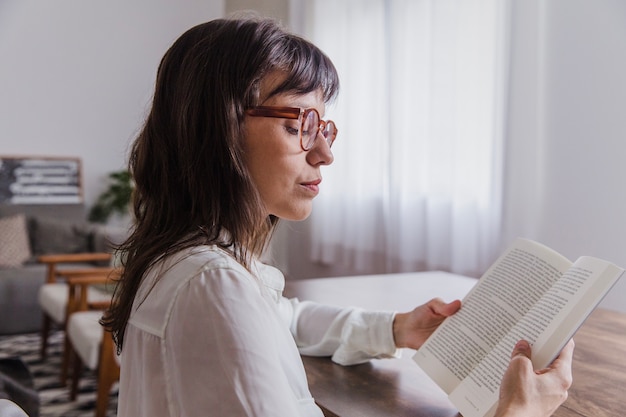 Foto gratuita mujer con gafas leyendo vista lateral