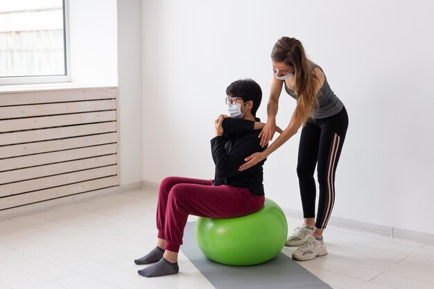 Mujer con gafas recuperándose después de tener covid en fitness ball