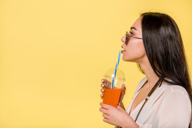 Foto gratuita mujer, en, gafas de sol, bebida, jugo