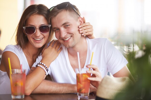 Mujer con gafas de sol bebiendo un cóctel con su novio