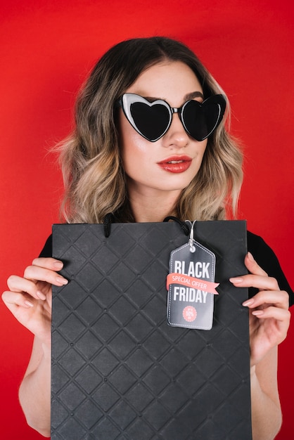 Mujer con gafas de sol de corazón y bolso negro de viernes