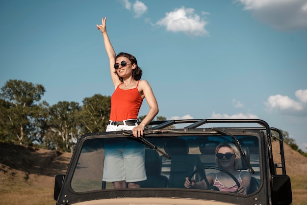 Mujer con gafas de sol divirtiéndose mientras viaja en coche