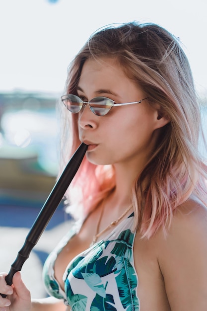 Foto gratuita una mujer con gafas de sol fuma una cachimba
