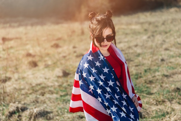 Mujer en gafas de sol lanzando bandera estadounidense sobre