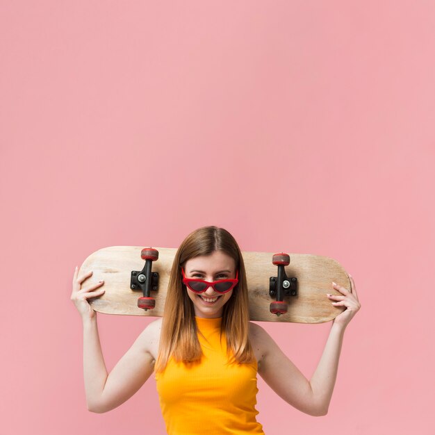 Mujer con gafas de sol y patineta con espacio de copia