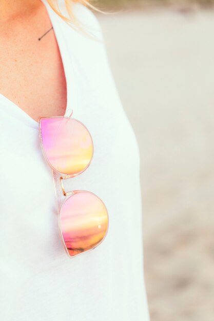 Mujer con gafas de sol rosa en la playa.