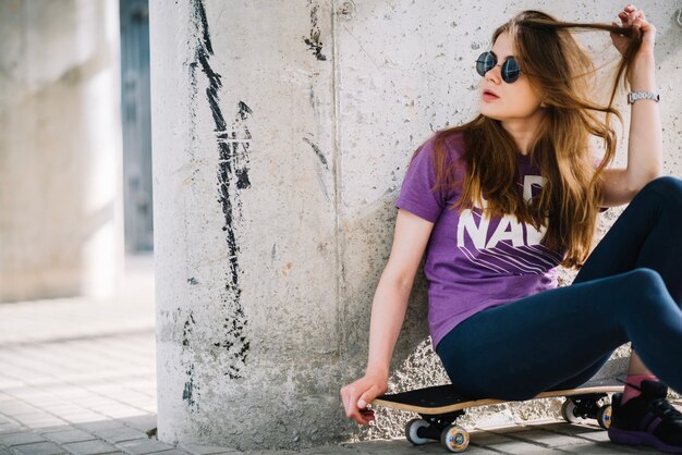 Mujer con gafas de sol sentado en patineta