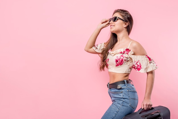 Mujer en gafas de sol sonriendo y sosteniendo la maleta