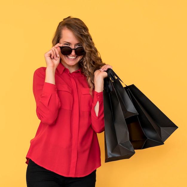 Mujer con gafas de sol y sosteniendo bolsas de la compra.