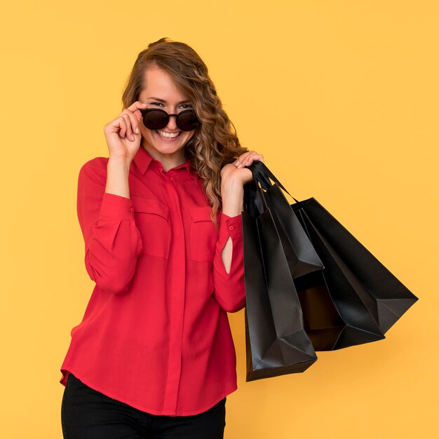 Mujer con gafas de sol y sosteniendo bolsas de la compra.