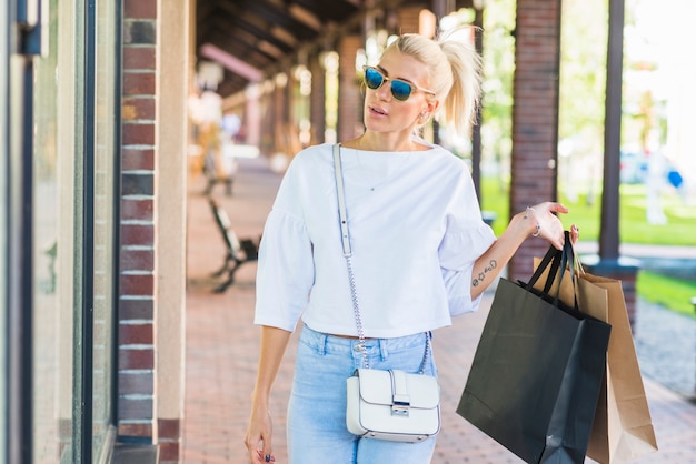 Mujer, en, gafas de sol, tenencia, bolsas