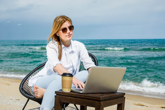 Foto gratuita mujer con gafas de sol trabajando en la playa