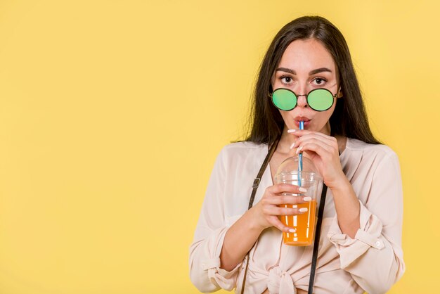 Mujer en gafas de sol verdes con jugo