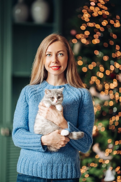 Una mujer con un gato se abraza en casa.