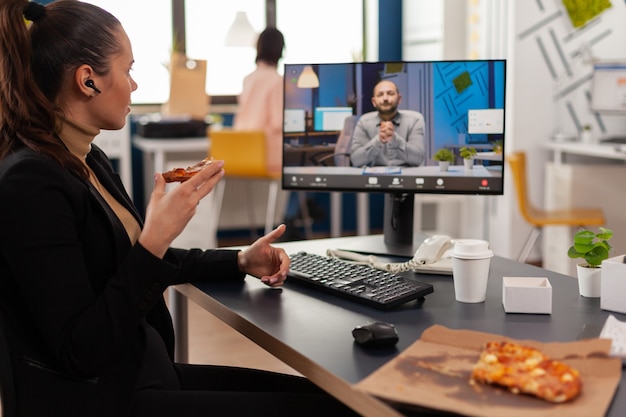 Mujer gerente discutiendo con el empresario remoto durante la videollamada en línea con almuerzo de entrega