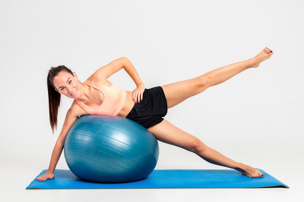 Mujer en el gimnasio en la colchoneta con entrenamiento de pelota que rebota