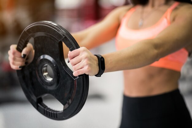 Mujer en el gimnasio haciendo ejercicio con la placa de peso
