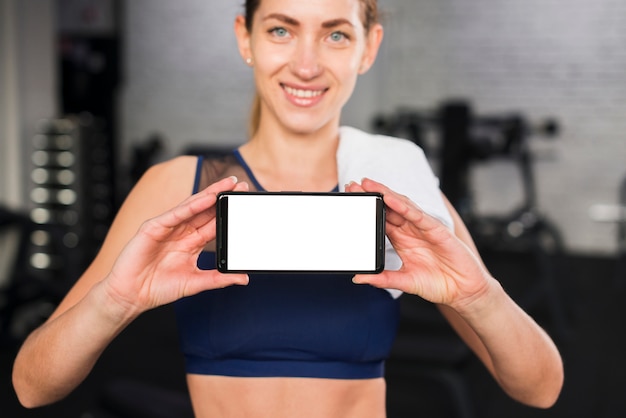 Foto gratuita mujer en gimnasio con plantilla de smartphone