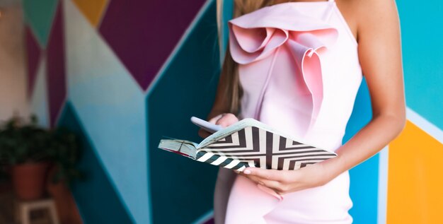 Mujer glamorosa en elegante vestido rosa con portátil y smartphone