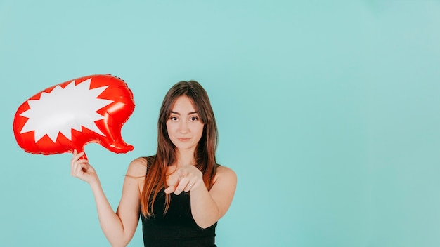 Mujer con globo de discurso apuntando a la cámara