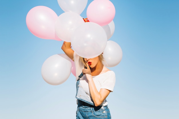 Mujer con globos gesticulando silencio