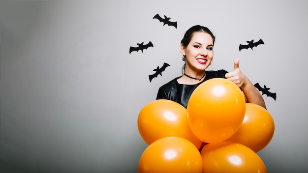 Foto gratuita mujer con globos haciendo gestos con el pulgar hacia arriba