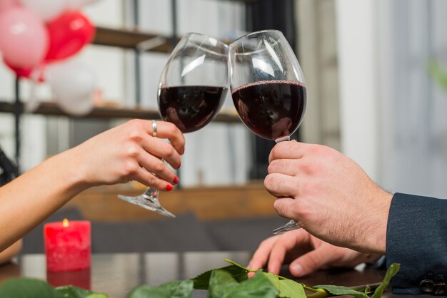 Mujer golpeando copas de vino con el hombre en la mesa