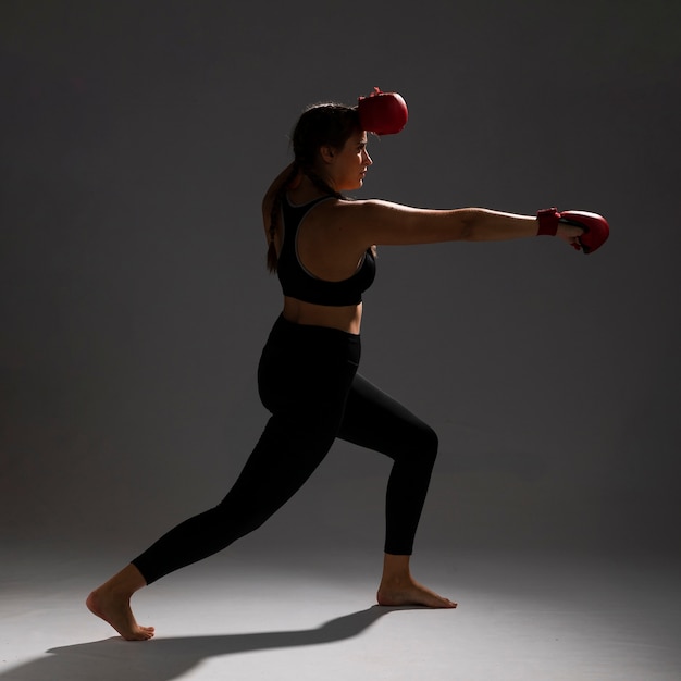 Foto gratuita mujer golpeando de lado con guantes de box