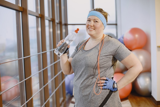 Foto gratuita mujer gorda a dieta, fitness. dama con cuerda. mujer en traje deportivo gris.