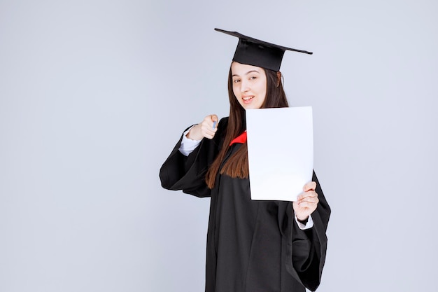 Mujer con gorro de graduación con lápiz y hoja vacía. Foto de alta calidad