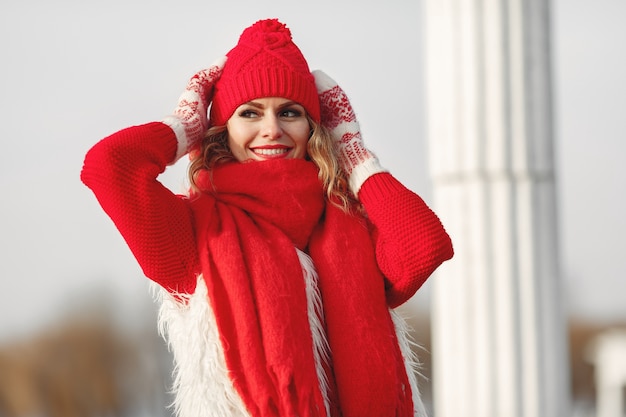 Mujer con gorro de invierno tejido y bufanda mirando a la cámara con una sonrisa