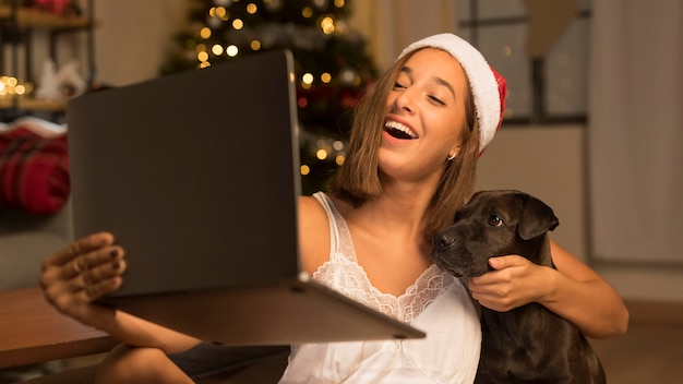 Mujer con gorro de Papá Noel mostrando su perro a personas de guardia usando laptop