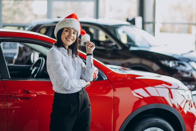 Mujer con gorro de Papá Noel en Navidad en la sala de exposición de automóviles