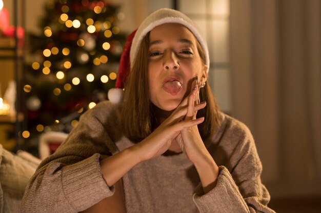 Mujer con gorro de Papá Noel posando mientras muestra su lengua
