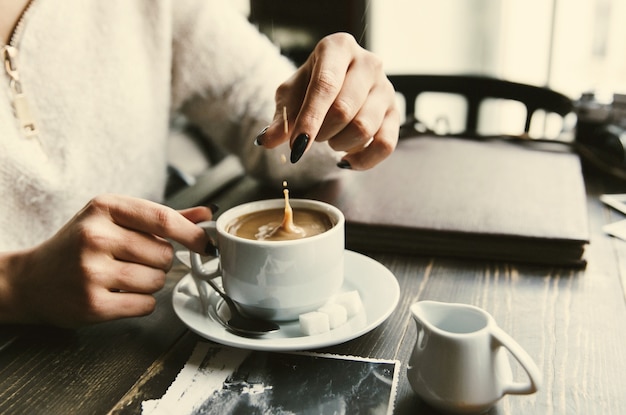 Mujer gotas de azúcar en una taza de café