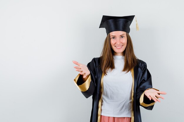 Mujer graduada dando abrazo a la cámara en ropa casual, uniforme y alegre. vista frontal.