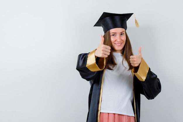 Mujer graduada mostrando doble pulgar hacia arriba en ropa casual, uniforme y alegre. vista frontal.