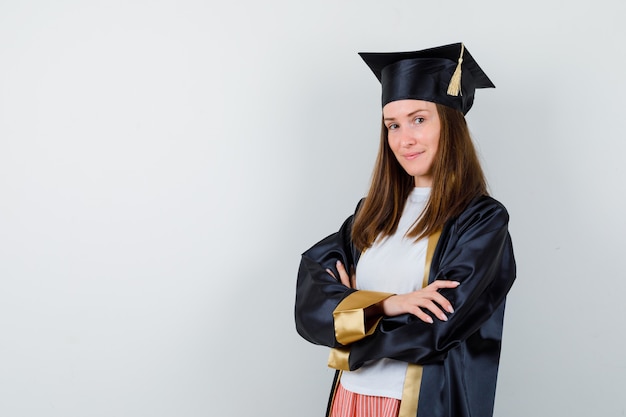 Mujer graduada de pie con los brazos cruzados en ropa casual, uniforme y confiada. vista frontal.