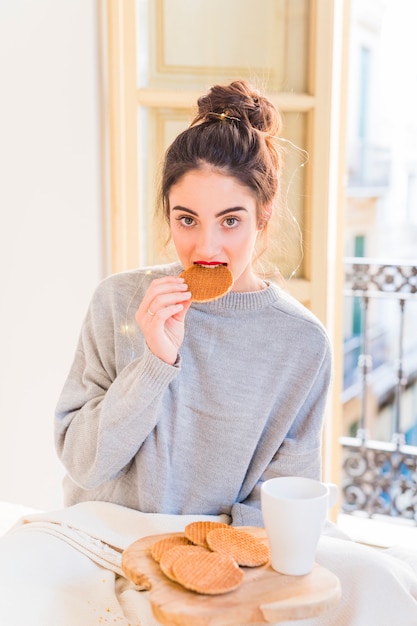 Mujer en gris comiendo galletas